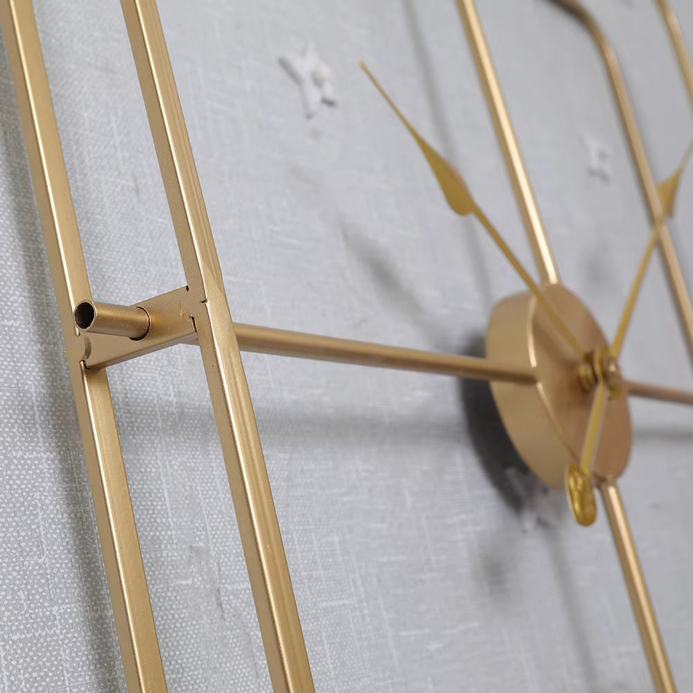 Détail d'une horloge murale carrée en métal avec aiguilles dorées et structure géométrique minimaliste